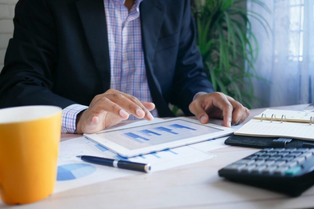 a man in black suit using a white tablet on a table