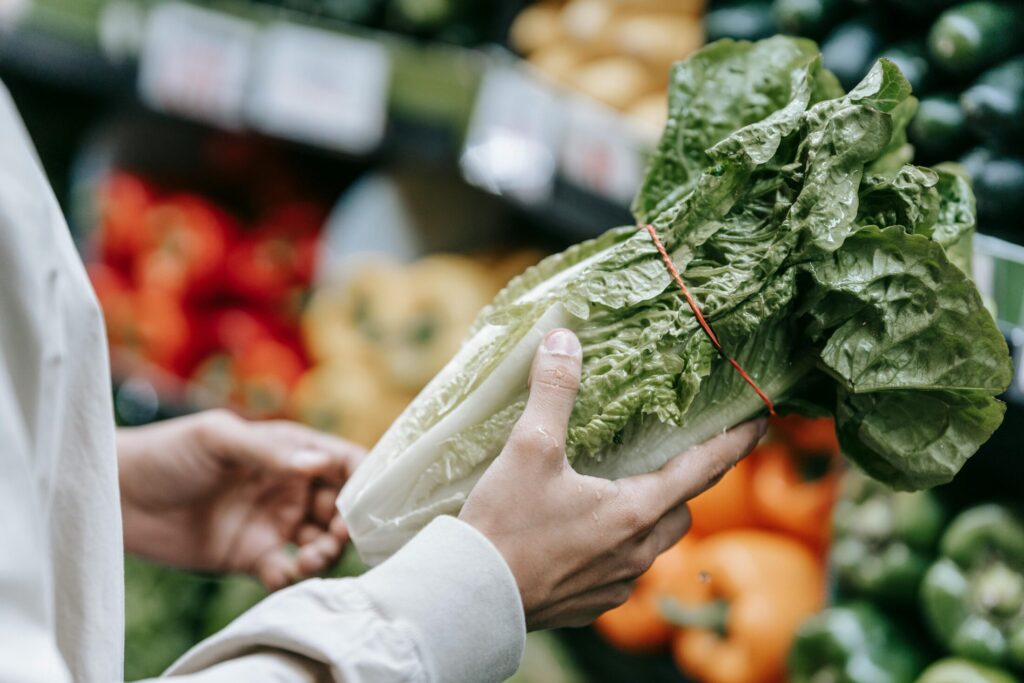 a customer checking a letuce in the vegetable section of the grocery