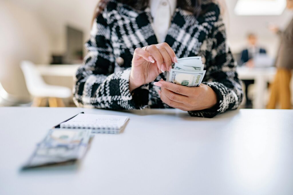 a person in white and black plaid jacket holding banknotes
